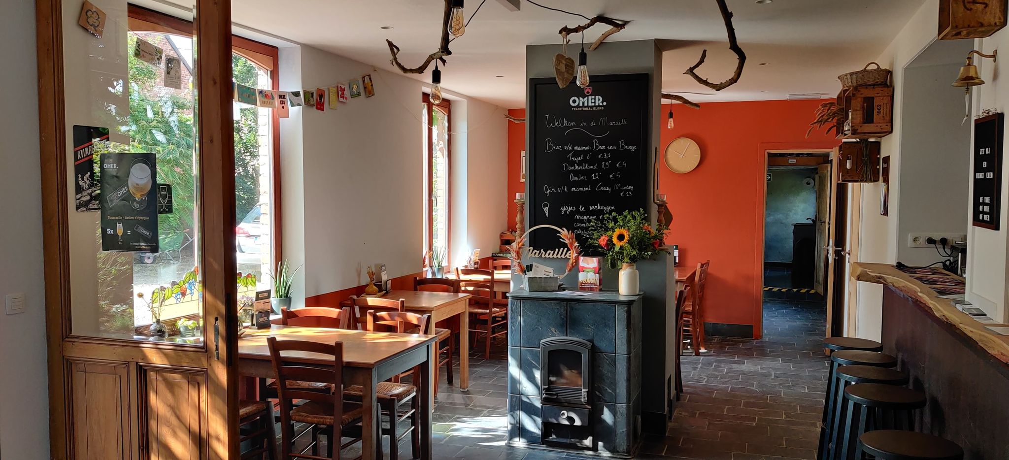 Een zicht op het interieur van het café, een zicht op de hoeveelheid stoelen en de gezellige haard.